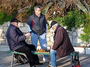 Some young men playing chess on a bench.