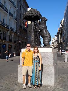 Jay and Kelly in front of a statue of a bear climbing the madrono tree -- the symbol of Madrid.