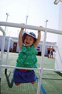 Capri having fun hanging from some bars on the top deck of the ferry